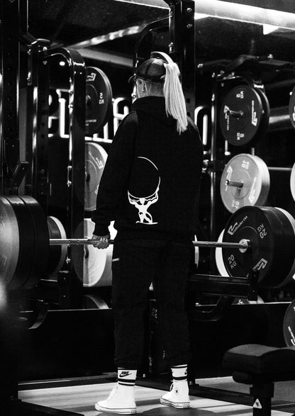 Female athlete wearing the heavyweight black and white Atlas Apparel gym hoodie.