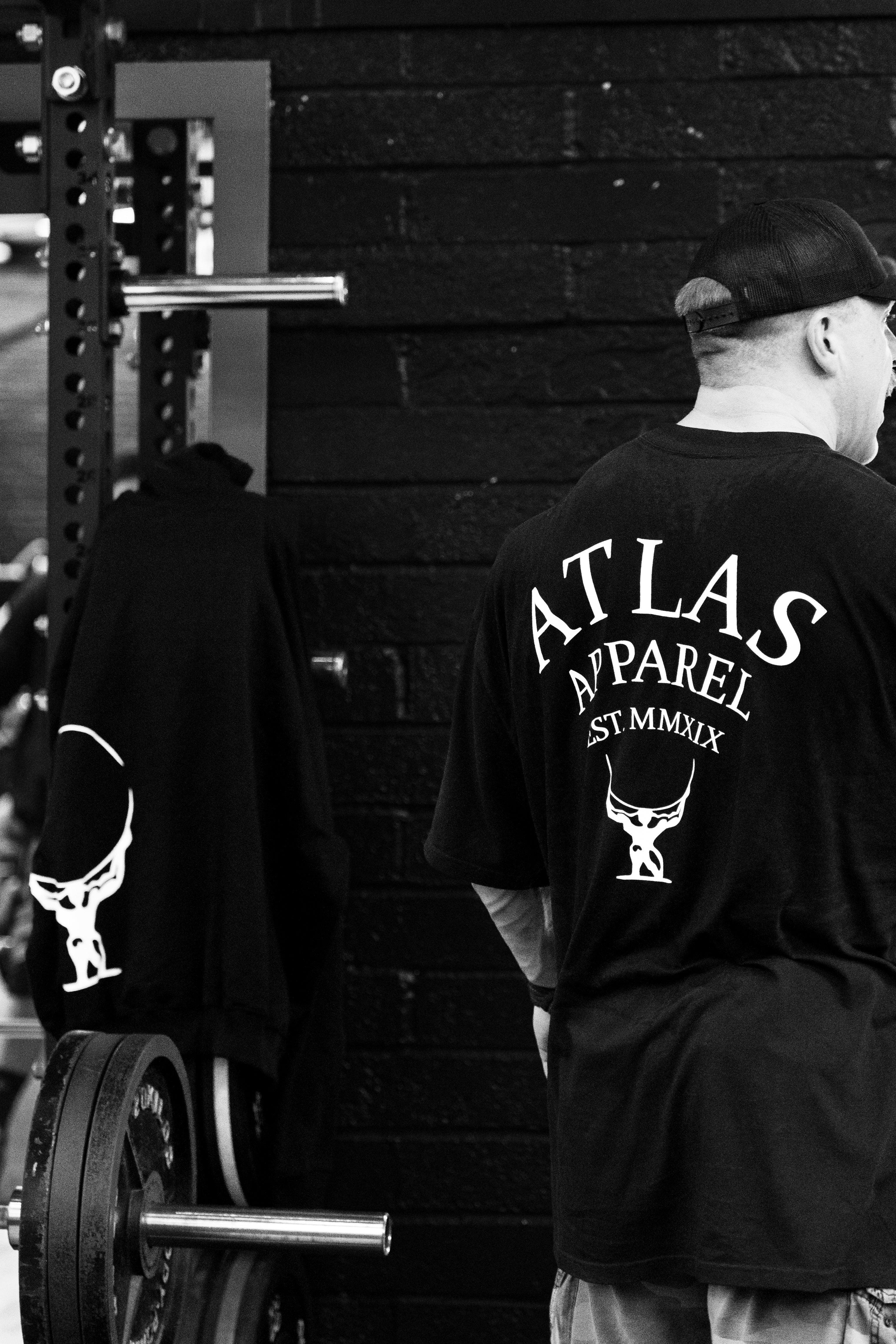 Man standing with his back to the camera, wearing the black over sized t shirt.