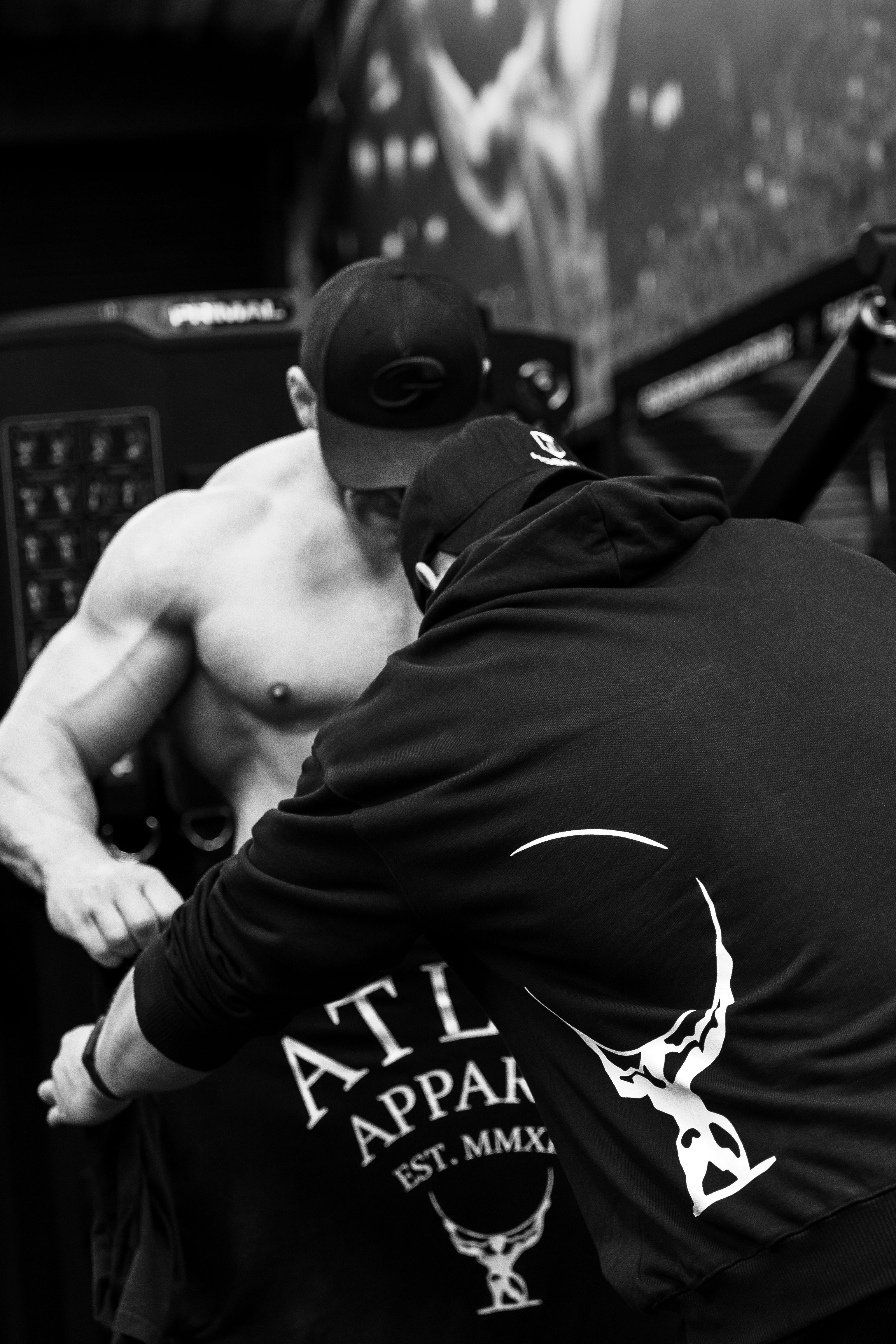 Two athletes trying. on the Atlas Apparel black t shirt and hoodie